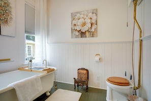 A bathroom with a bathtub, toilet, and a chair. - Pet-friendly Historic Home: Downtown Breaux Bridge (Breaux Bridge)