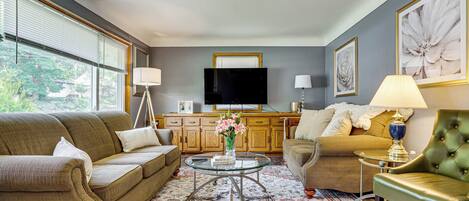 A living room with a sofa, armchair, coffee table, and a television.