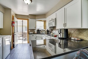 A kitchen with white cabinets, a microwave, a coffee maker, and a large island with a sink. - South Saint Paul Duplex w/ Deck & Gas Grill (South St. Paul)