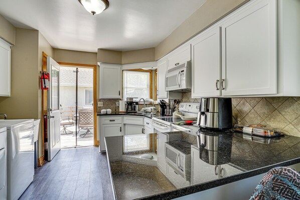 A kitchen with white cabinets, a microwave, a coffee maker, and a large island with a sink. - Deck & Shared Yard! Relaxing South Saint Paul Home (South St. Paul)