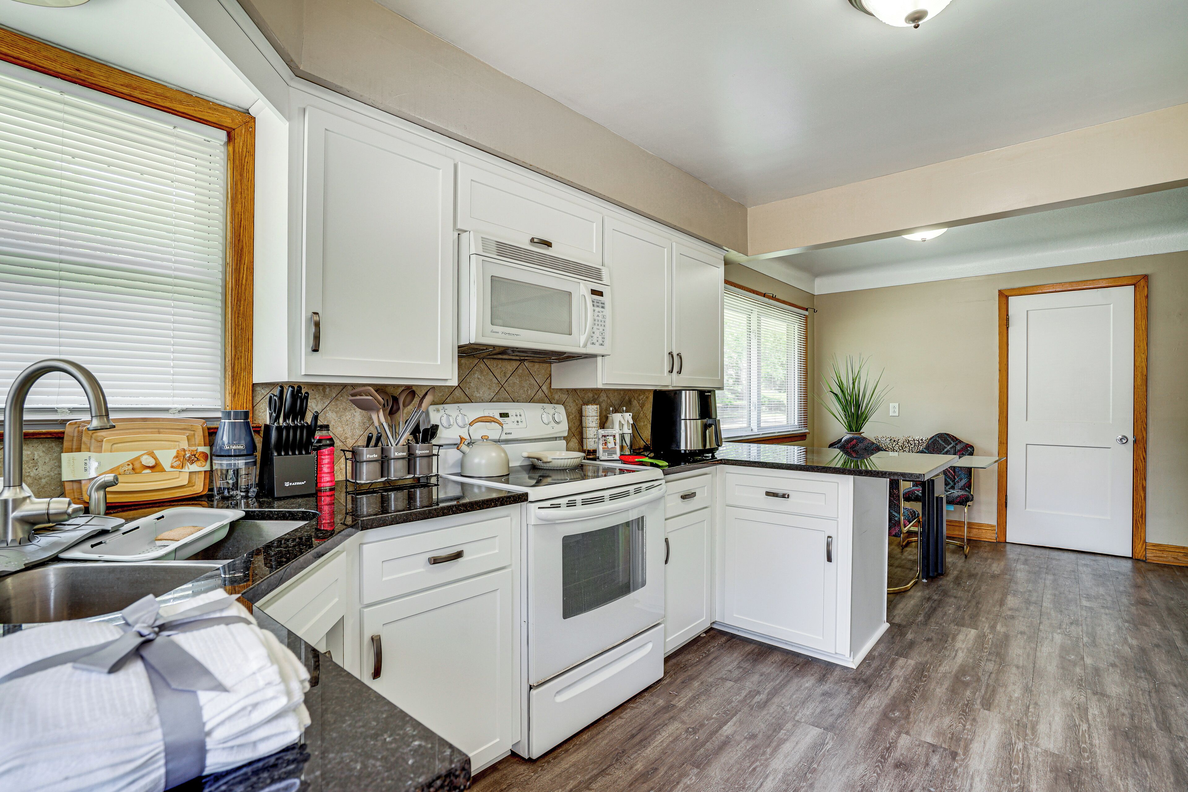 A kitchen with white cabinets, a microwave, stove, and a sink.