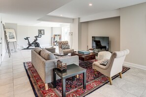 A living room with a sofa, armchairs, a coffee table, a TV, and a bike in the background. - 4 Mi to Iplay America! Home w/ Horse Farm Views (Freehold)