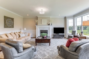 A living room with a fireplace, a television, and a large window.