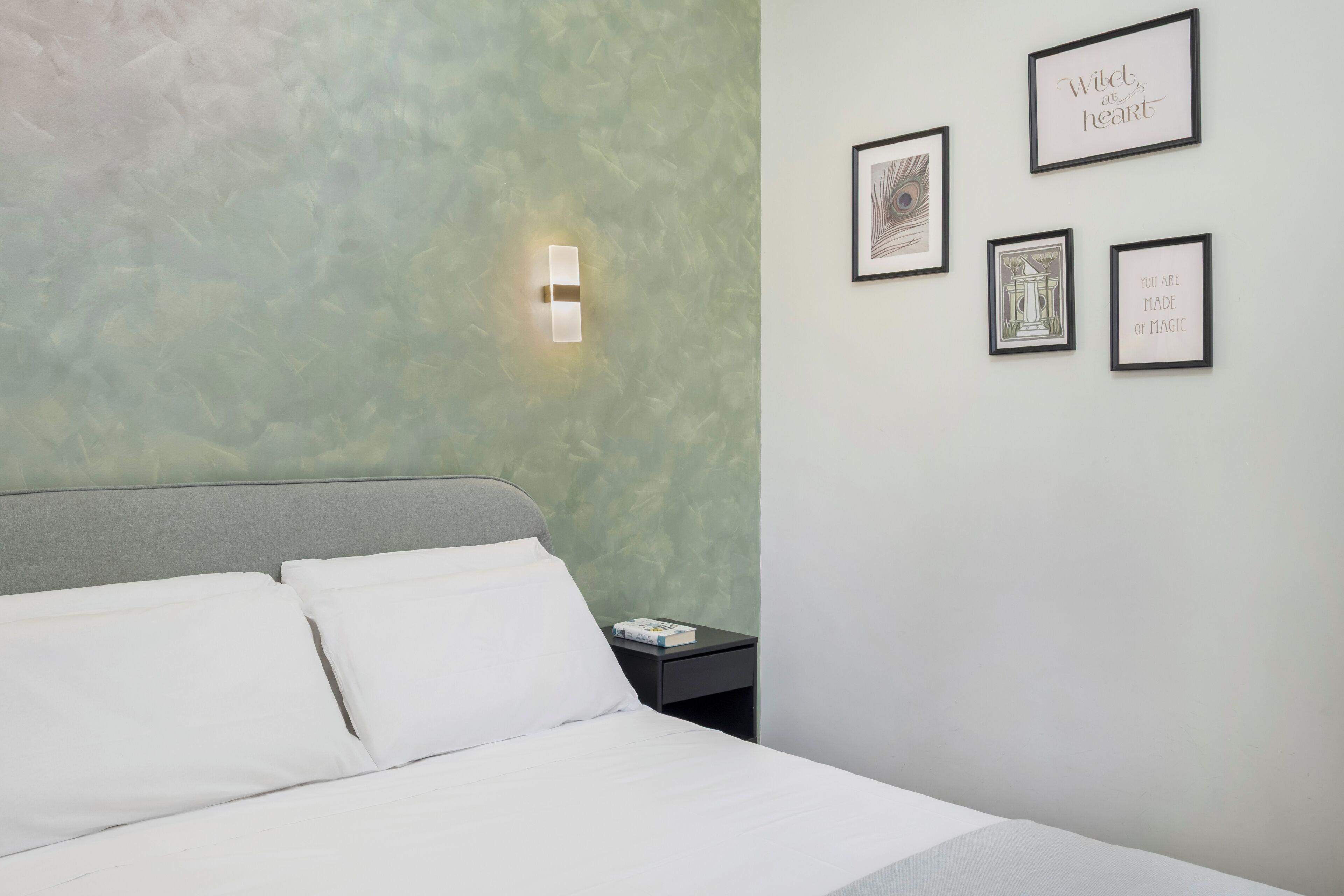 Una habitación de hotel con una cama, una mesita de noche y una pared decorada con cuadros.
