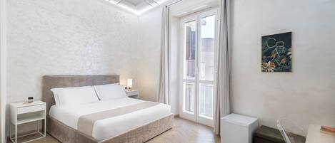 Ein modernes Schlafzimmer mit Bett, Nachttischen, einem Schreibtisch und einem Kühlschrank.