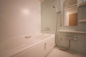 Un baño con una bañera blanca, ducha y espejo sobre el lavabo.