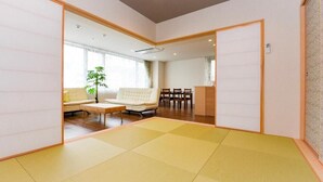 A traditional Japanese-style room with tatami flooring, a sofa, a coffee table, and a dining area with chairs. - Otaru Ryo An (Otaru City)