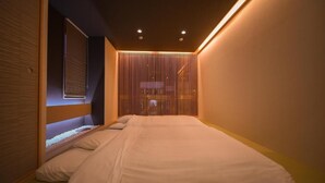 A bedroom with a bed, a window with blinds, and a wall with vertical slats. - Otaru Ryo An (Otaru City)