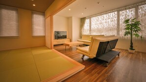 A modern living room with a tatami mat, a sofa, a TV, and a potted plant. - Otaru Ryo An (Otaru City)