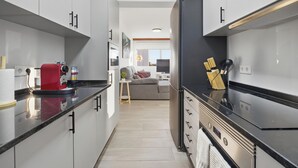 A modern kitchen with white cabinets, a red coffee machine, and a stainless steel range hood. - Little Paradise - Funchal (Funchal)