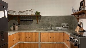 Una cocina con armarios de madera, una estufa empotrada y una lámpara colgante.
