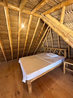Ein Einzelbett in einem Zimmer mit Bambusdecke und Holzboden.