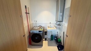 Ein kleiner Hauswirtschaftsraum mit Waschmaschine, Spüle und Wischhalterung.