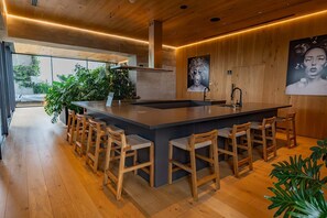 A modern kitchen with a central island, bar stools, wooden flooring, and large windows. - w Boutique 1BR in the Heart of Cuauht moc (Mexico City)