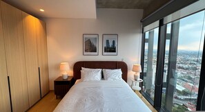 A modern hotel room with a large bed, two bedside lamps, a wooden wardrobe, and a city view. - w Boutique 1BR in the Heart of Cuauht moc (Mexico City)