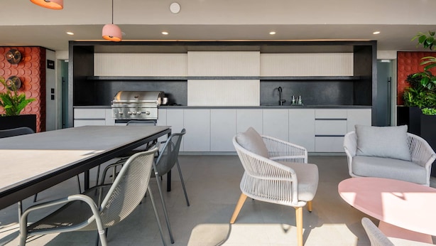 A modern kitchen with a built-in grill, white cabinetry, and a dining area with wicker chairs and a table. - w Calm Cozy 1BR w Balcony in Tabacalera (Mexico City)