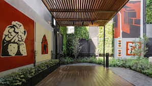A wooden deck leading to a covered area with a modern architectural design, including a pergola and a wall with abstract art. - w Calm Cozy 1BR w Balcony in Tabacalera (Mexico City)