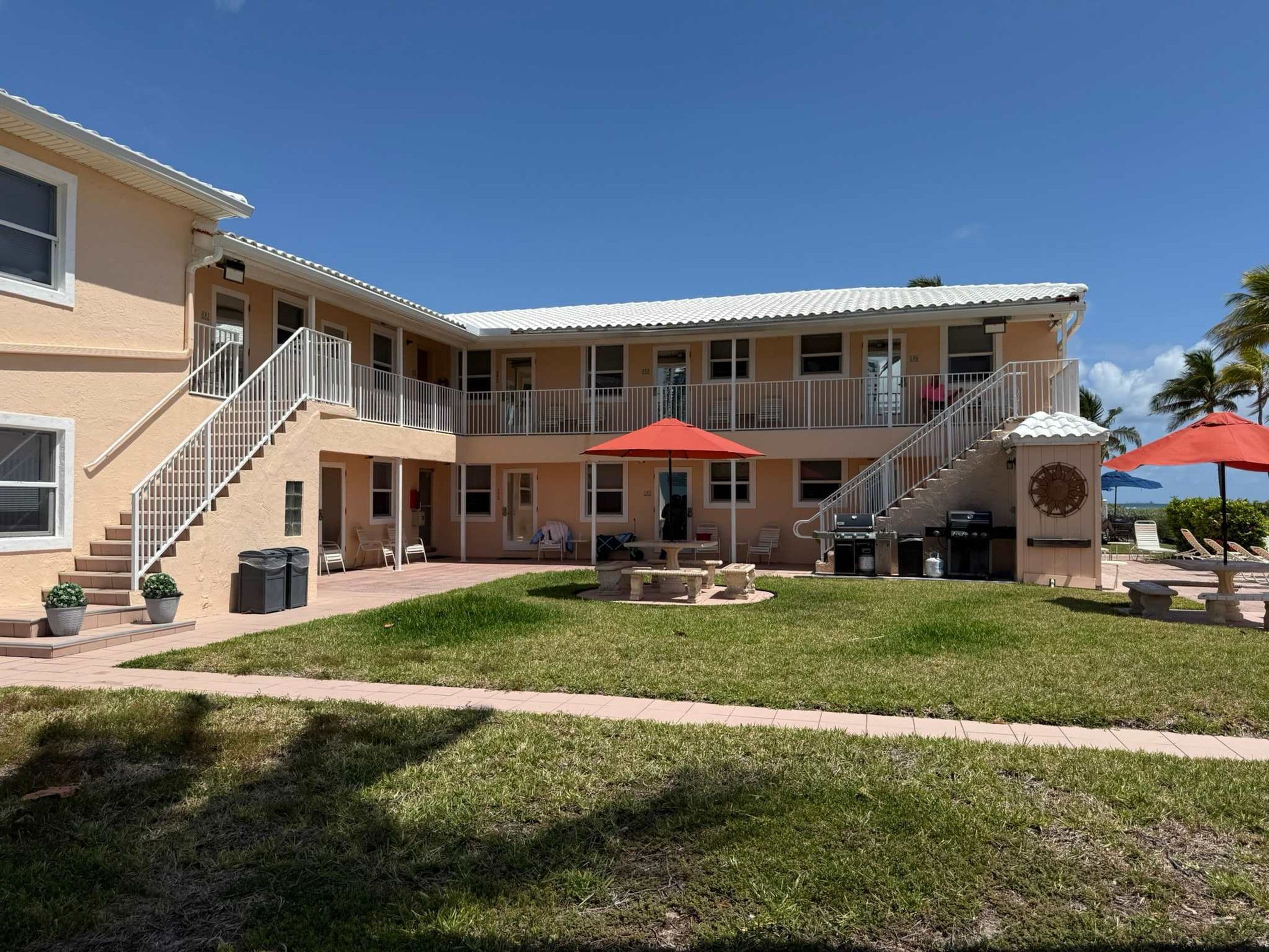 A two-story building with a covered patio area, outdoor seating, and a barbecue station.