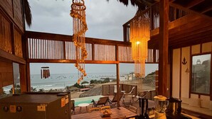 A kitchen with a view of the beach, wooden furniture, and a hanging light fixture. - w Relaxing Oceanfront 5BR in Punta Veleros (Los Organos)