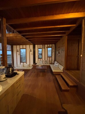 Um quarto acolhedor com teto de madeira, um sofá, uma mesa de centro e uma janela com cortinas.