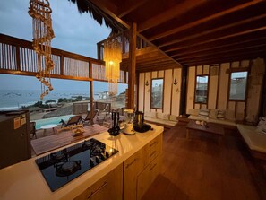 Una cocina moderna con vista al océano, muebles de madera y un comedor también con vista.