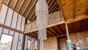 A wooden interior with a high ceiling, a hanging chandelier, and a balcony. - w Relaxing Oceanfront 5BR in Punta Veleros (Los Organos)
