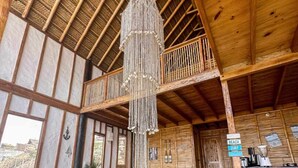 Interior de madera con techo alto, una lámpara colgante y un balcón.