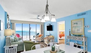 Ein Zimmer mit Balkon, Fernseher, Esstisch und Stuhl.