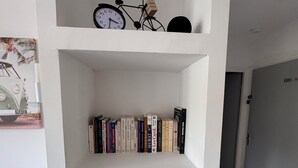 Uma estante branca com livros, um globo e uma bicicleta.