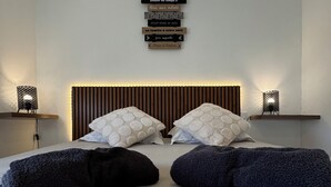 Uma cama com cabeceira, duas mesas de cabeceira e objetos decorativos fixados na parede.