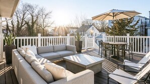 Eine Terrasse mit einer Couch, Stühlen, einem Tisch und einem Sonnenschirm.