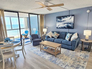 A living room with a sofa, chairs, a coffee table, and a view of the ocean through large windows. - Direct Oceanfront Condo with Outdoor Pool - Amazing Beachfront location! Pyramid Building 7D (Ocean City)