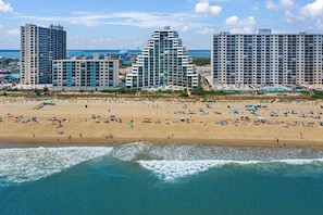 A beach with high-rise buildings in the background, a sandy shore, and waves approaching the beach. - Direct Oceanfront Condo with Outdoor Pool - Amazing Beachfront location! Pyramid Building 7D (Ocean City)