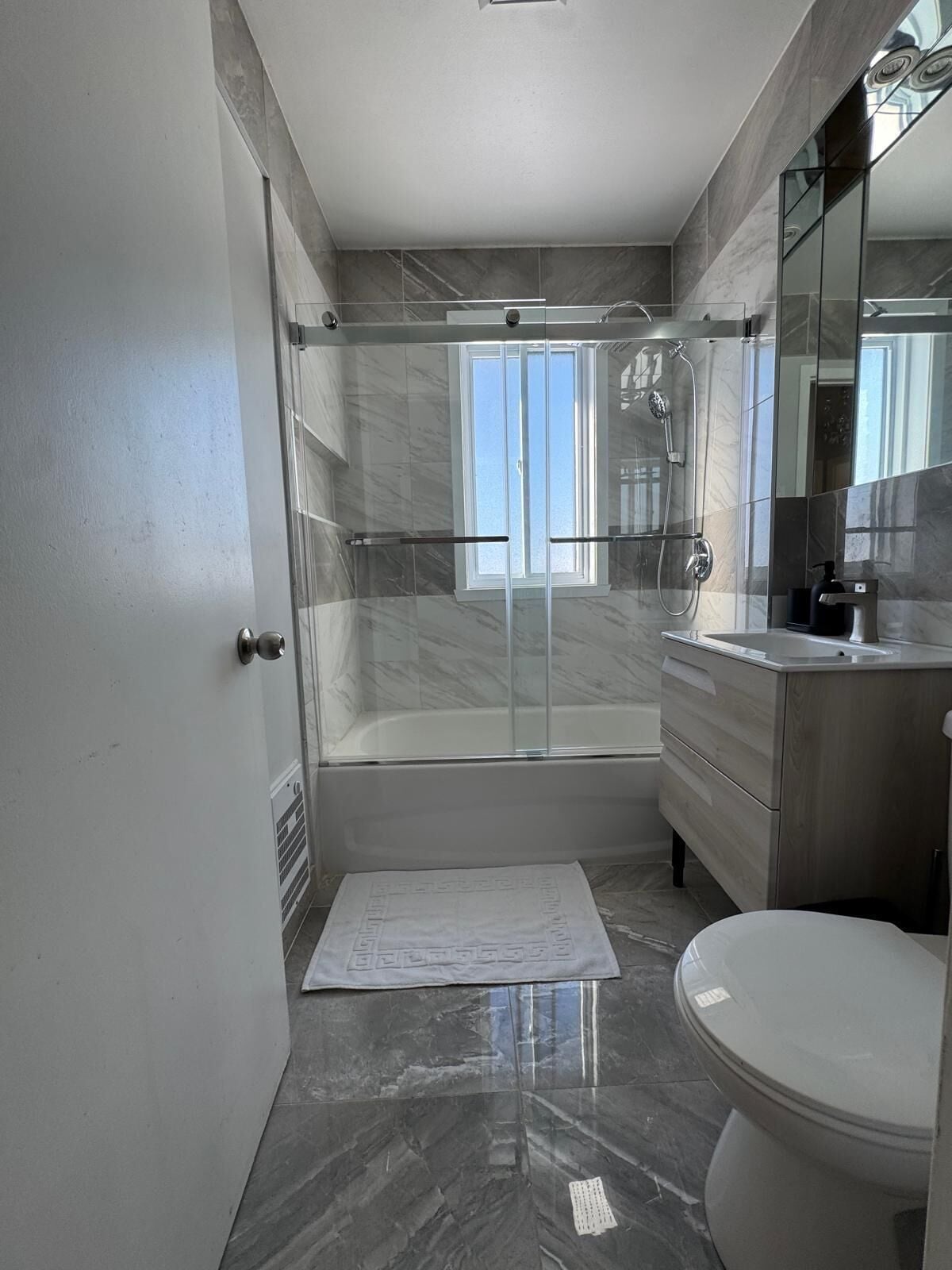 A modern bathroom with a glass-enclosed shower, a bathtub, and a toilet.. Cozy Home Near Place Bell