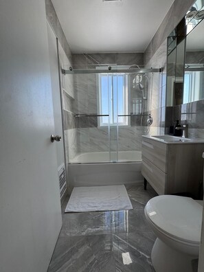 Une salle de bain moderne avec une douche à parois de verre, une baignoire et des toilettes.