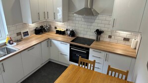 Una cocina moderna con armarios blancos, una encimera de madera, una estufa negra y una mesa de comedor con sillas.