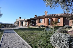 A two-story house with a brick exterior, a tiled roof, and a paved driveway.