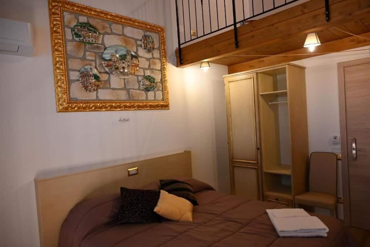 Un dormitorio con cama, armario, espejo y un adorno en la pared.