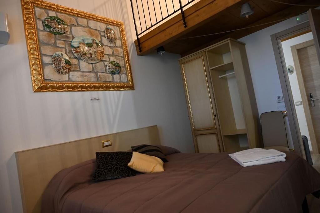 Une chambre d’hôtel avec un lit, une œuvre d’art encadrée au mur, une armoire et une porte.