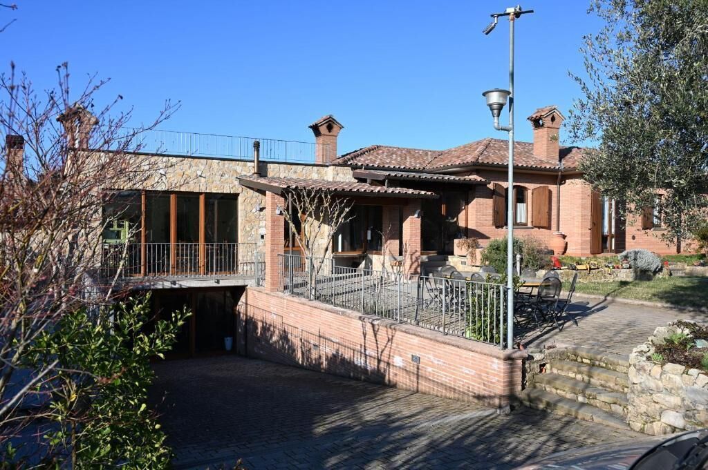 A traditional building with a stone facade, a covered patio, and a metal railing.