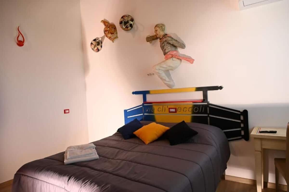 Un dormitorio con cama, escritorio y una pared decorada.