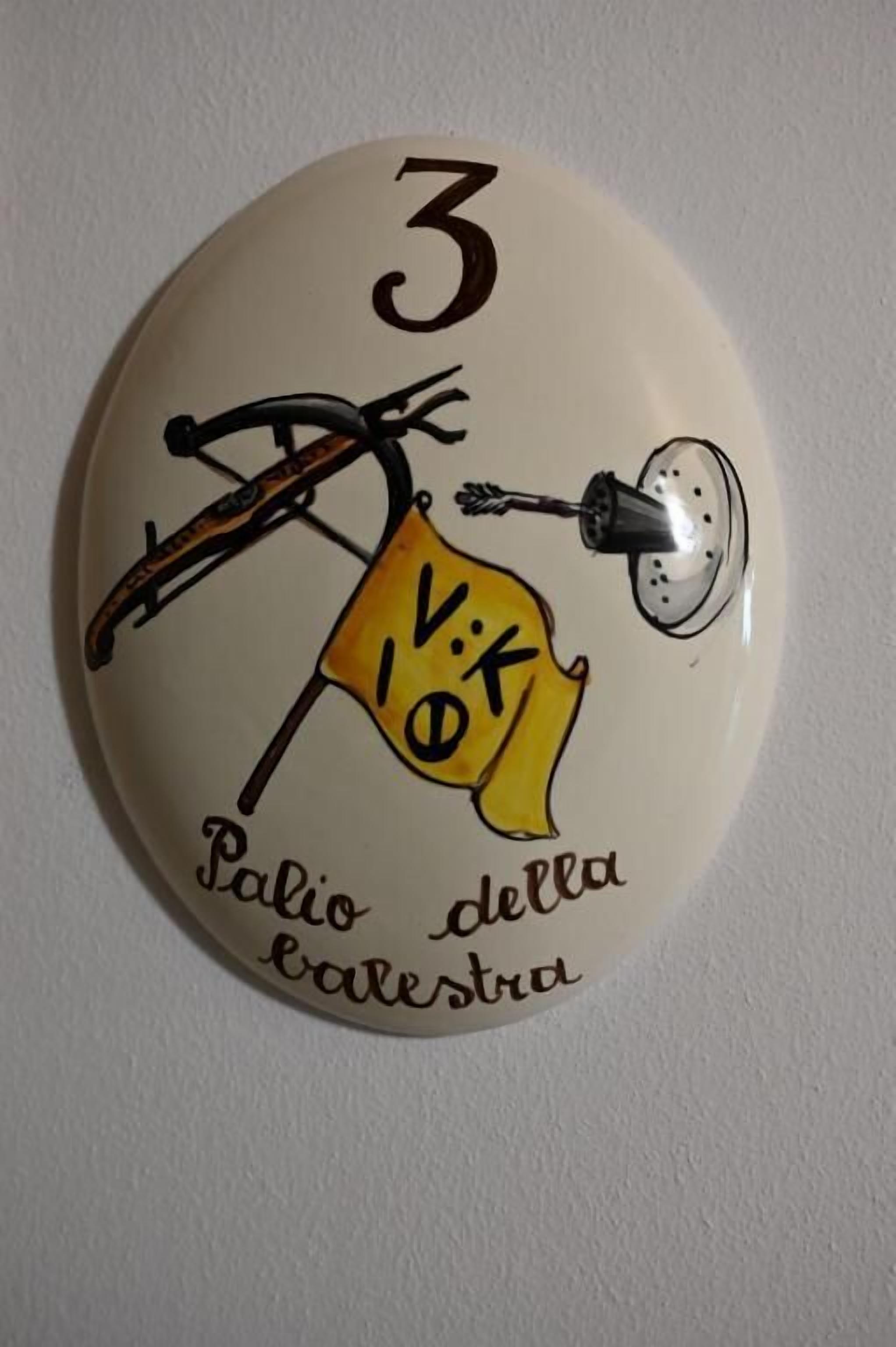 Una placa mural con una bicicleta y una bandera, con las etiquetas '3' y 'Vik' respectivamente, y el texto 'Palo della Calesta'.