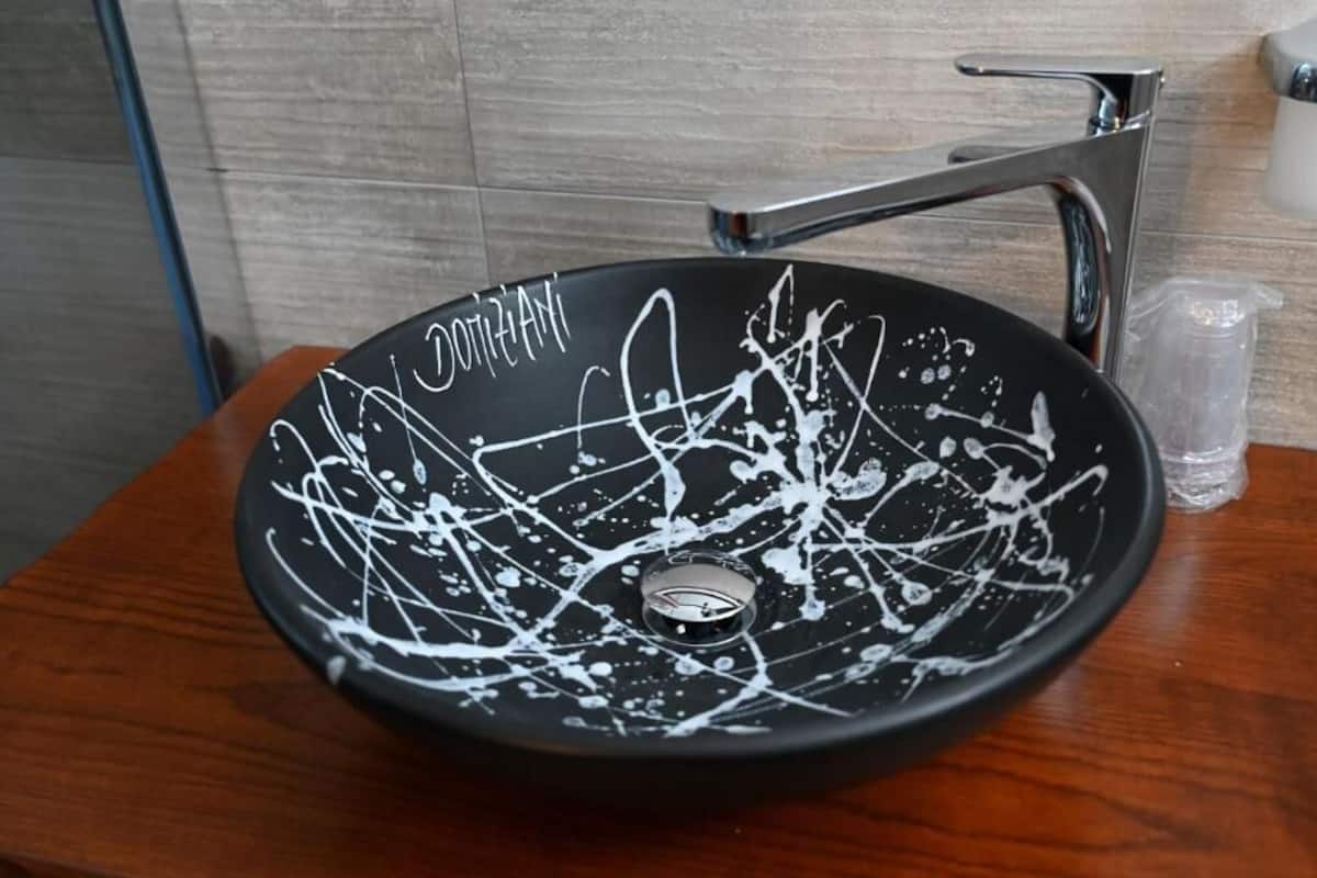 Un lavamanos negro con grafiti blanco sobre una encimera de madera.