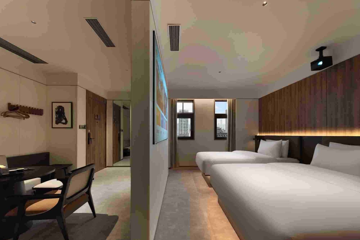 A modern hotel room with a bed, a desk, and a chair.