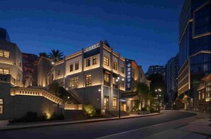 A hotel with a modern facade, multiple floors, and a prominent entrance with steps. - Mist Wandering Courtyard  (Chongqing)
