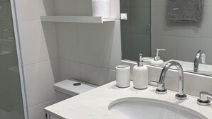 Un baño moderno con inodoro, lavamanos y ducha.
