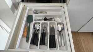Un cajón con divisiones que contiene diferentes utensilios de cocina.
