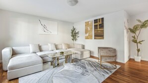 Una sala de estar moderna con un sofá seccional blanco, una mesa de centro de vidrio y un sillón gris.