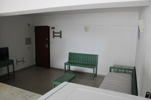 A room with a bed, a green bench, a small table, a television, and a door. - Apartment in Praia da Rocha (Portimão)