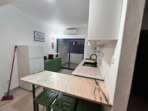 A compact kitchen with a marble countertop, a green bench, a white refrigerator, and a microwave on a green cabinet. - Apartment in Praia da Rocha (Portimão)